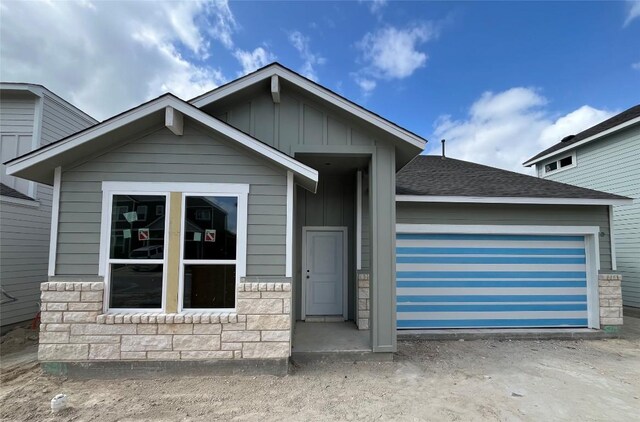5311 Bruno St, Round Rock, TX 78665 - view of front of house with board and batten siding, stone siding, a garage, and roof with shingles