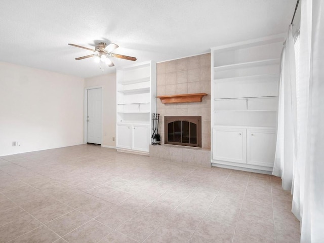 3513 Westchester Ave, Austin, TX 78759 - unfurnished living room with built in features, a ceiling fan, a tile fireplace, light tile patterned floors, and a textured ceiling