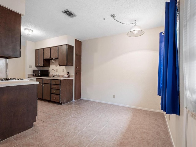 3513 Westchester Ave, Austin, TX 78759 - kitchen with black microwave, light countertops, dark brown cabinetry, a textured ceiling, and light tile patterned floors