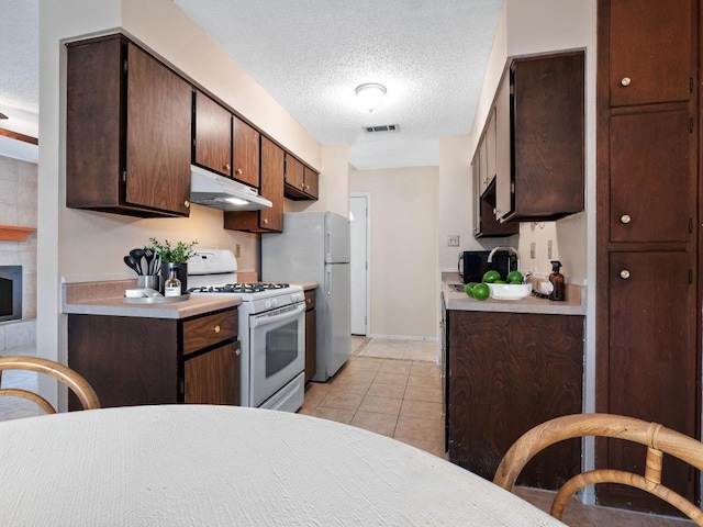 3513 Westchester Ave, Austin, TX 78759 - kitchen featuring white appliances, under cabinet range hood, a textured ceiling, light countertops, and light tile patterned floors