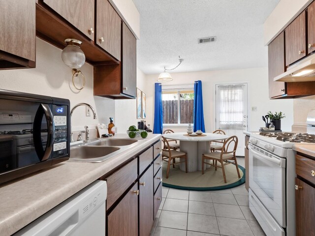 3513 Westchester Ave, Austin, TX 78759 - kitchen featuring white appliances, a sink, light countertops, light tile patterned floors, and a textured ceiling