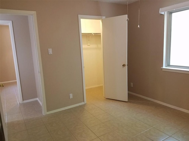 3513 Westchester Ave, Austin, TX 78759 - unfurnished bedroom featuring a walk in closet, light tile patterned flooring, a closet, and baseboards