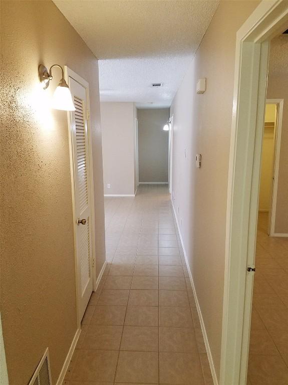 3513 Westchester Ave, Austin, TX 78759 - corridor with light tile patterned flooring, a textured ceiling, and baseboards