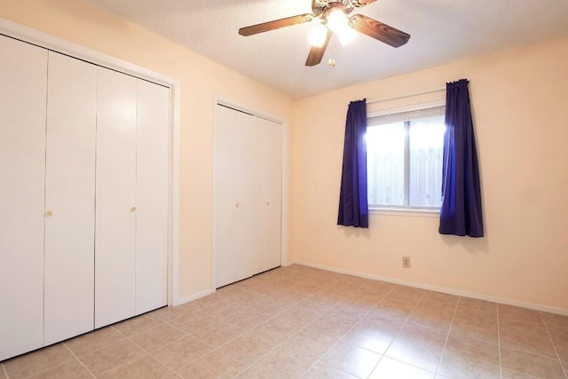 3513 Westchester Ave, Austin, TX 78759 - unfurnished bedroom with multiple closets, ceiling fan, baseboards, light tile patterned floors, and a textured ceiling