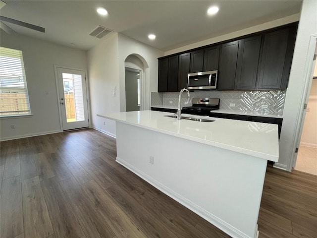 8525 Wellspring Loop, Round Rock, TX 78665 - kitchen with appliances with stainless steel finishes, arched walkways, decorative backsplash, dark wood finished floors, and recessed lighting