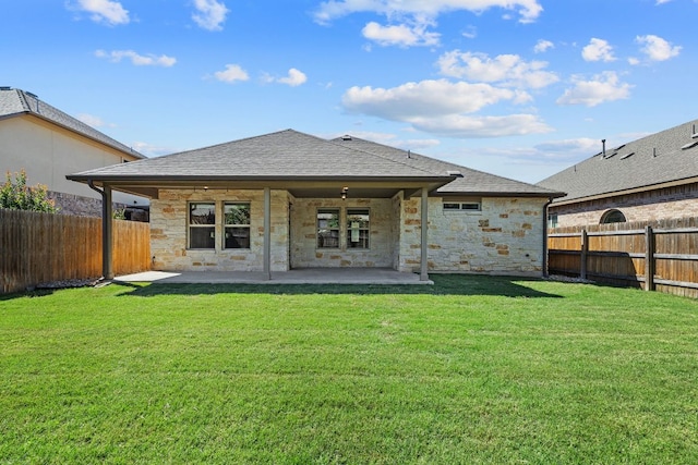 back of property with stone siding, a patio area, and roof with shingles
