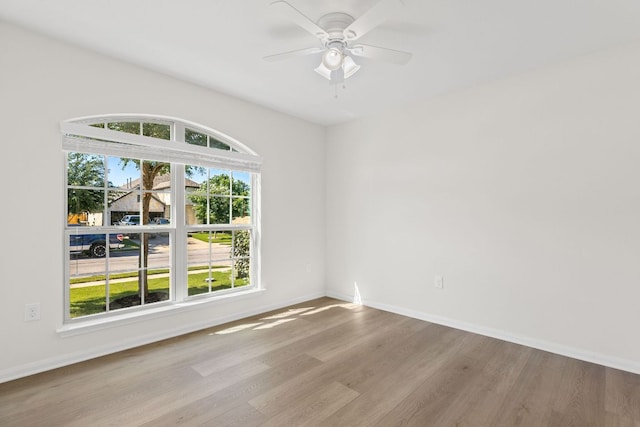 unfurnished room with wood finished floors, baseboards, and a ceiling fan