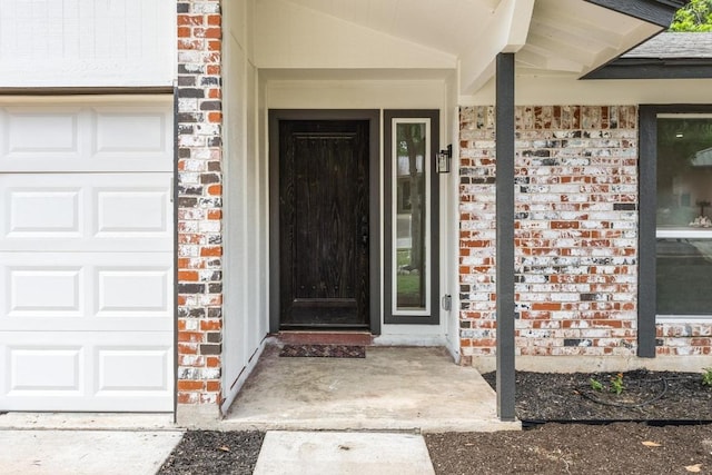 property entrance featuring brick siding, a garage, and covered porch