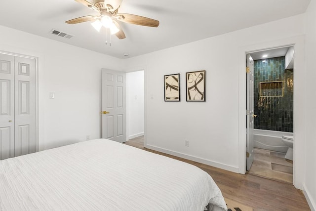bedroom with wood finished floors, baseboards, ensuite bath, and a ceiling fan