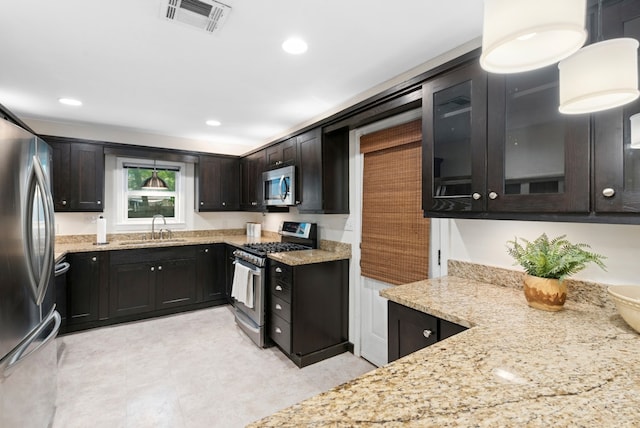2603 Hidalgo St, Austin, TX 78702 - kitchen with stainless steel appliances, a sink, light stone counters, dark brown cabinetry, and glass insert cabinets