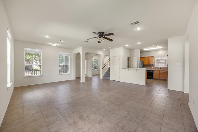 unfurnished living room with arched walkways, recessed lighting, ceiling fan, light tile patterned floors, and baseboards
