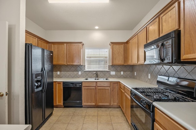 kitchen featuring black appliances, a sink, light tile patterned flooring, decorative backsplash, and light countertops