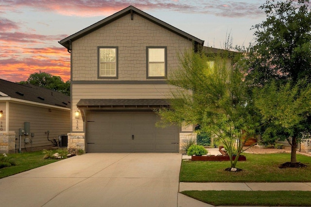 view of front of house featuring concrete driveway, central AC unit, an attached garage, stone siding, and a lawn