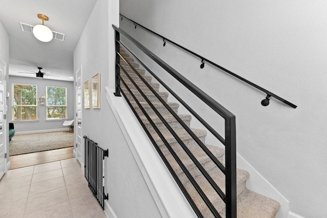 stairway with tile patterned flooring, baseboards, and a ceiling fan