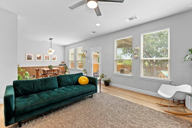 living area featuring wood finished floors, plenty of natural light, a ceiling fan, and baseboards