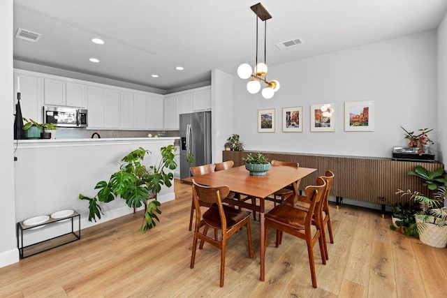 dining space with light wood finished floors, recessed lighting, and a chandelier