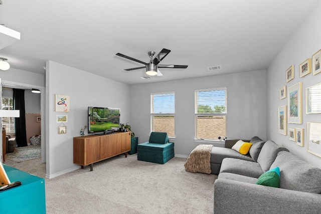 living area featuring light colored carpet, a ceiling fan, and baseboards