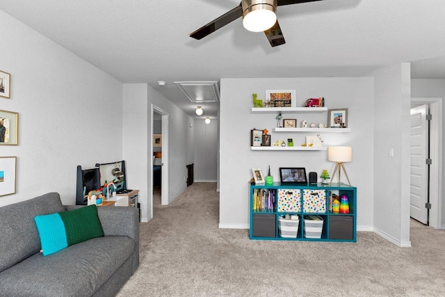living room with attic access, carpet flooring, a ceiling fan, and baseboards