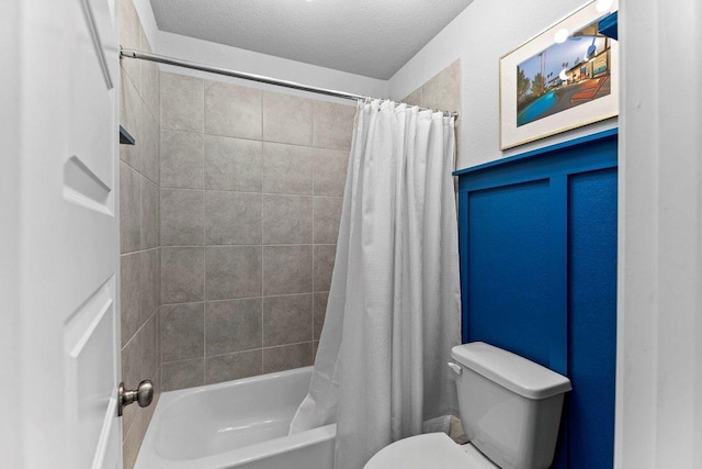 bathroom featuring toilet, shower / tub combo, and a textured ceiling