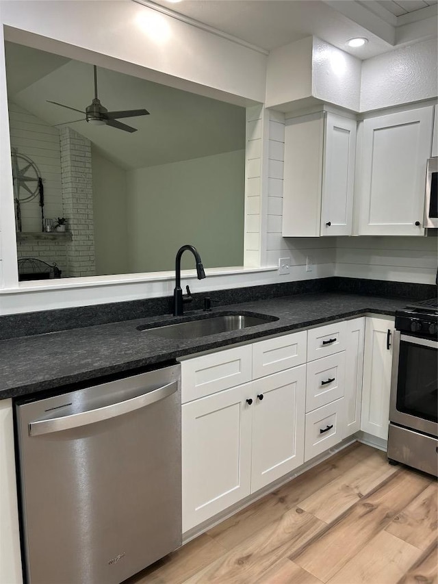 kitchen with stainless steel appliances, a sink, light wood finished floors, white cabinets, and a ceiling fan
