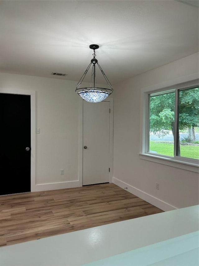 unfurnished dining area with baseboards and light wood-style floors