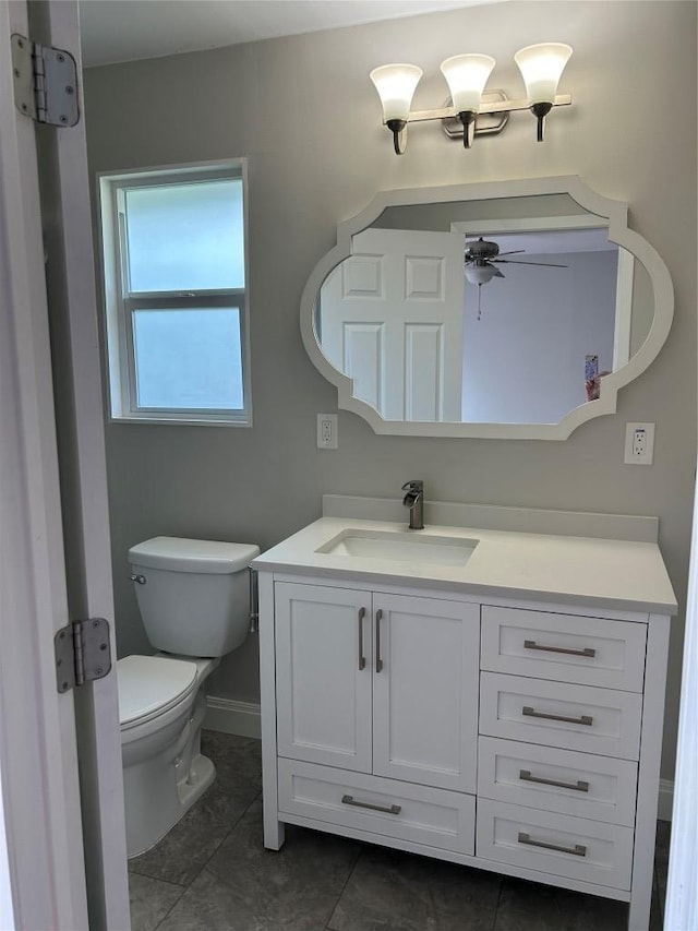 half bath with vanity, toilet, ceiling fan, tile patterned flooring, and baseboards