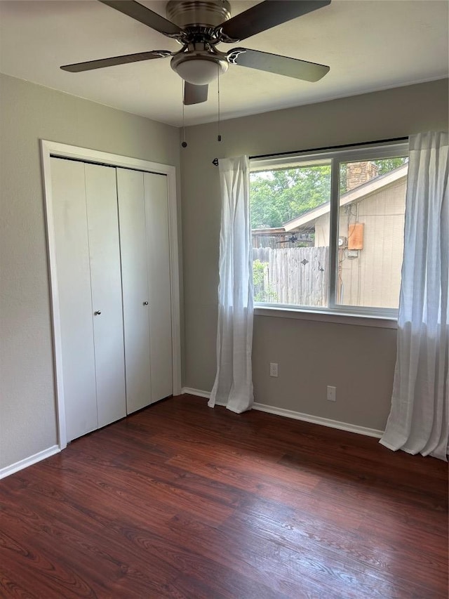 unfurnished bedroom with wood finished floors, baseboards, a closet, and ceiling fan