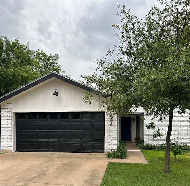 view of front facade featuring brick siding, a garage, driveway, a front lawn, and board and batten siding