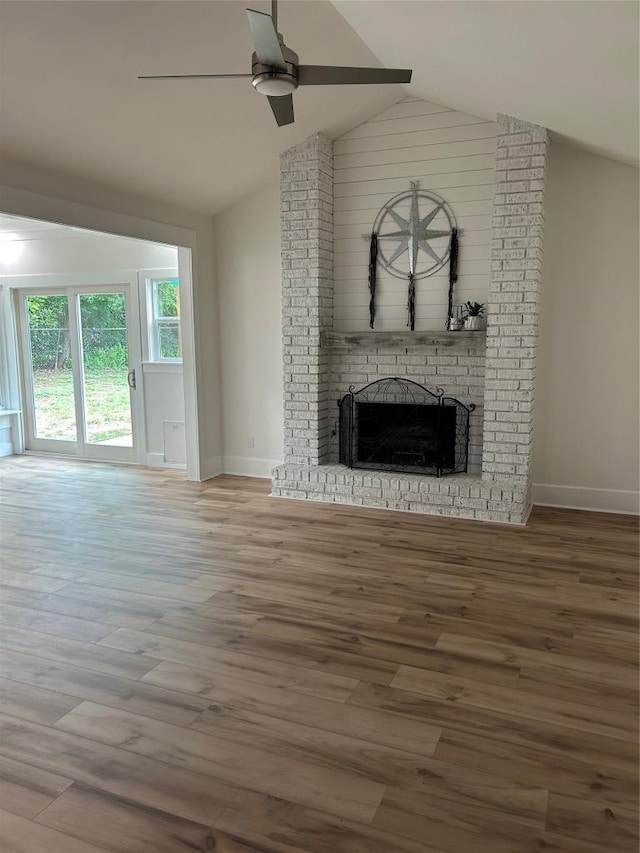 unfurnished living room with lofted ceiling, a fireplace, a ceiling fan, baseboards, and wood finished floors