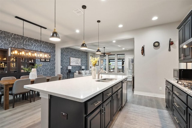 225 Escarpment Way, Cedar Park, TX 78613 - kitchen with an accent wall, a sink, wallpapered walls, stainless steel appliances, and light countertops