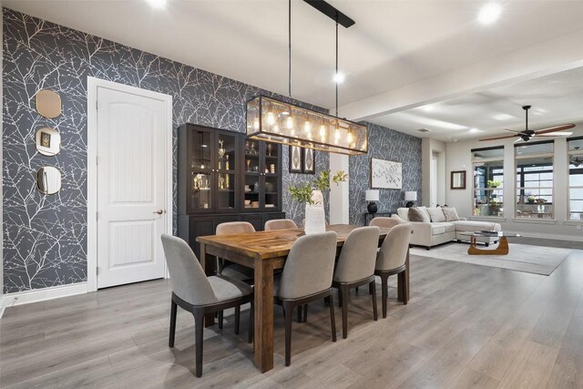 225 Escarpment Way, Cedar Park, TX 78613 - dining area with wallpapered walls, an accent wall, baseboards, wood finished floors, and ceiling fan
