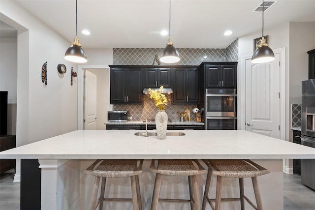 225 Escarpment Way, Cedar Park, TX 78613 - kitchen featuring a sink, stainless steel appliances, tasteful backsplash, a kitchen breakfast bar, and an island with sink