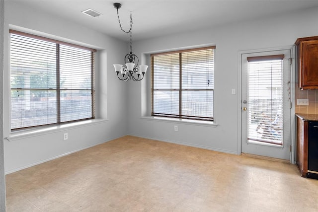 unfurnished dining area with a chandelier and baseboards
