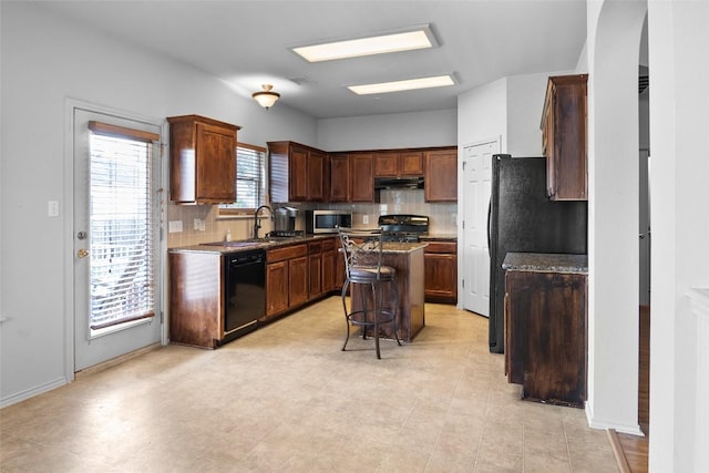 3908 Whitey Ford Way, Round Rock, TX 78665 - kitchen with black dishwasher, stainless steel microwave, under cabinet range hood, range, and decorative backsplash