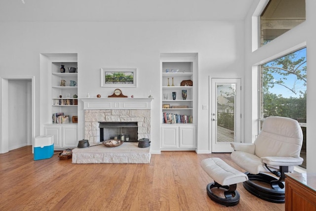 10978 W Cave Blvd, Dripping Springs, TX 78620 - living area with built in shelves, wood finished floors, baseboards, and a stone fireplace