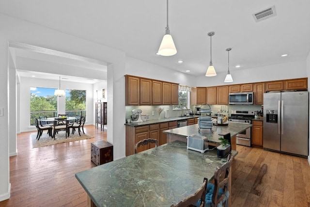 10978 W Cave Blvd, Dripping Springs, TX 78620 - kitchen with stainless steel appliances, dark countertops, a kitchen island, a sink, and light wood finished floors