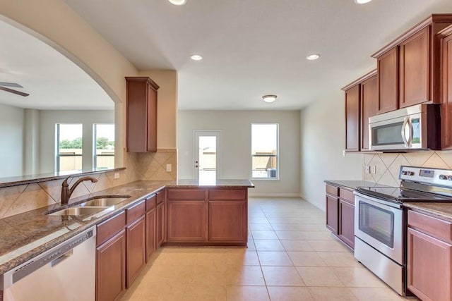 kitchen with appliances with stainless steel finishes, a sink, healthy amount of natural light, backsplash, and recessed lighting