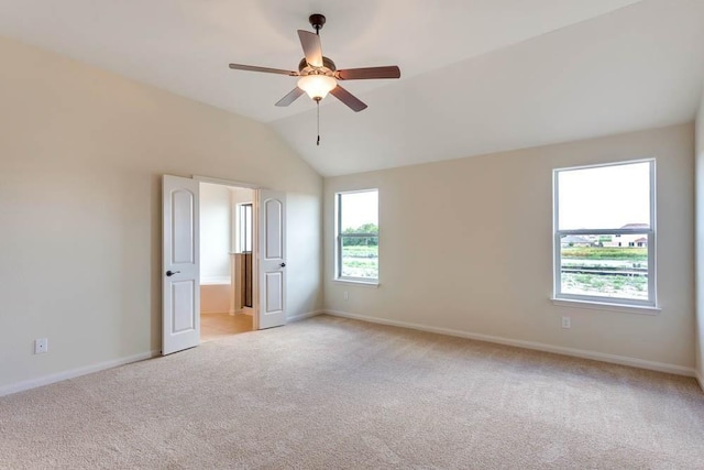 empty room with light carpet, a ceiling fan, lofted ceiling, and baseboards