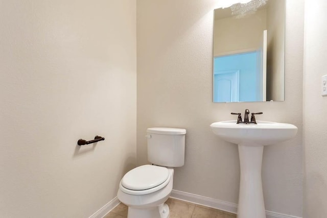 bathroom with baseboards, tile patterned floors, and toilet