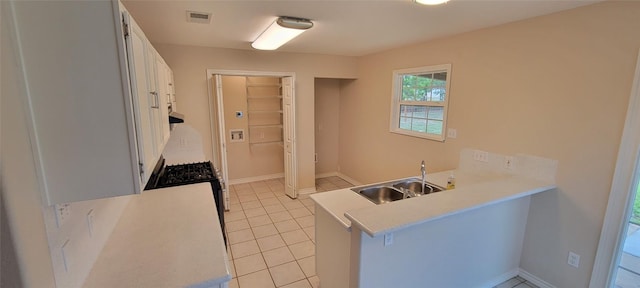 195 Cardinal Dr, Paige, TX 78659 - kitchen featuring a peninsula, white cabinetry, a sink, light tile patterned floors, and light countertops