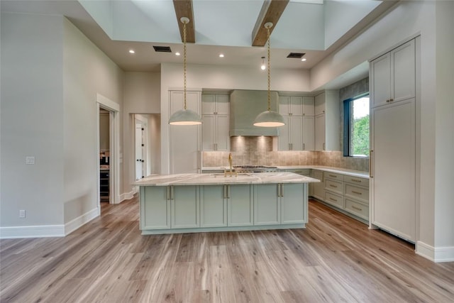 106 Edwards Cir, Horseshoe Bay, TX 78657 - kitchen featuring ventilation hood, light countertops, light wood-style floors, tasteful backsplash, and a kitchen island with sink