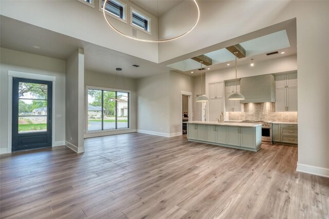 106 Edwards Cir, Horseshoe Bay, TX 78657 - unfurnished living room featuring a sink, baseboards, light wood-style flooring, and a high ceiling