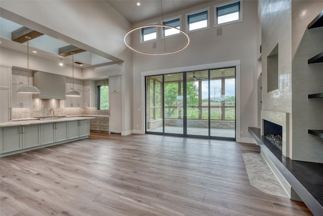 106 Edwards Cir, Horseshoe Bay, TX 78657 - unfurnished living room with a high ceiling, baseboards, light wood-style flooring, a fireplace with raised hearth, and recessed lighting