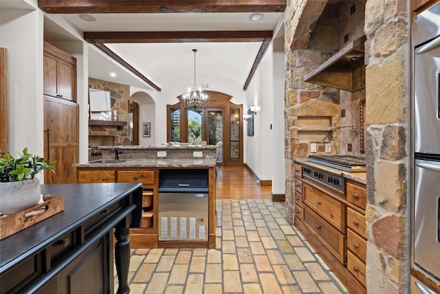 kitchen featuring a chandelier, arched walkways, stainless steel appliances, decorative light fixtures, and baseboards