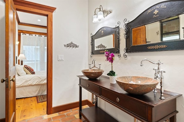 ensuite bathroom featuring baseboards and double vanity