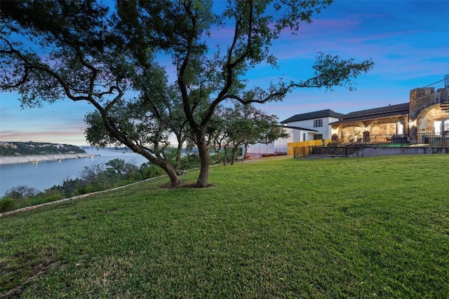 yard at dusk featuring a water view