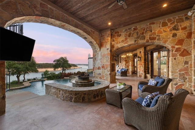 view of patio / terrace featuring fence, a water view, and a pool with connected hot tub