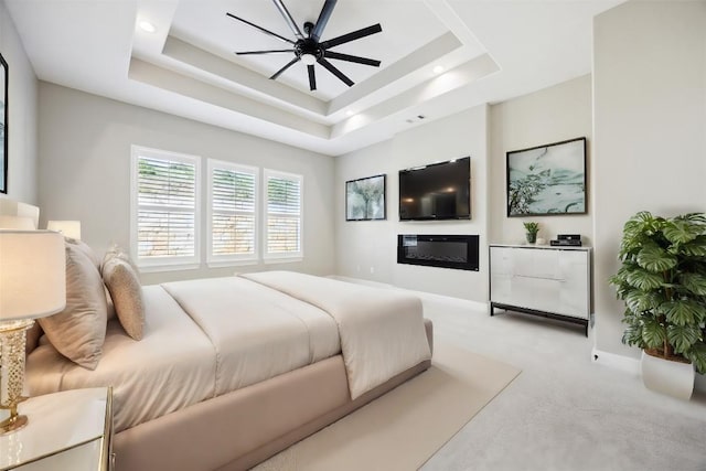 bedroom featuring a raised ceiling, carpet floors, and a ceiling fan