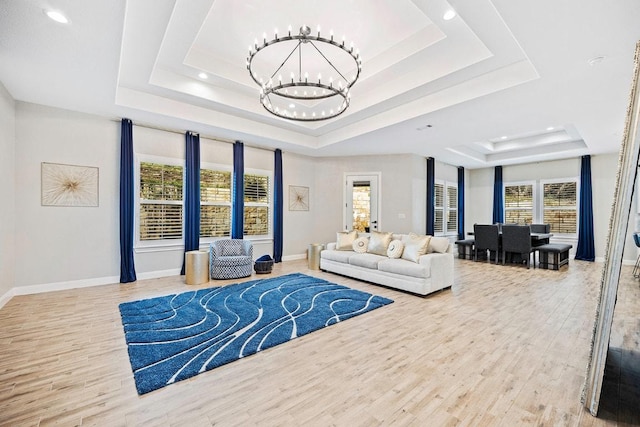 living area featuring a tray ceiling, a chandelier, recessed lighting, wood finished floors, and baseboards