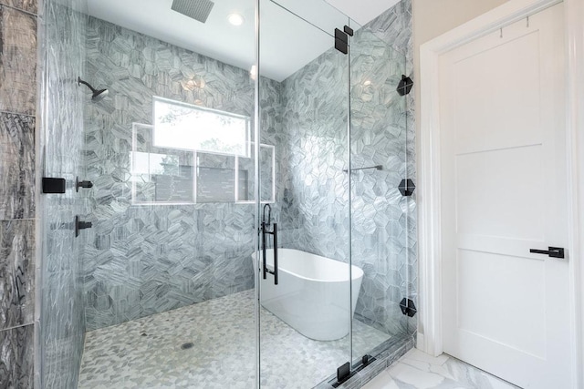 bathroom with a stall shower, marble look tile flooring, a freestanding bath, and recessed lighting